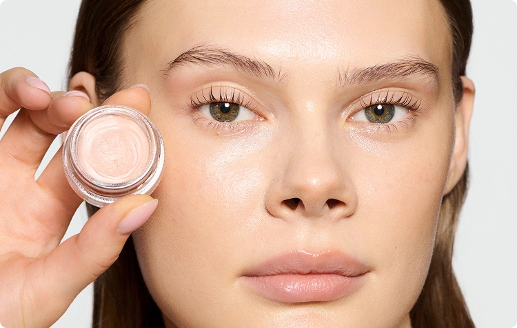 Woman wearing wake me up cream and holding the jar